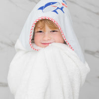 Child wearing a white hooded towel with a blue shark design on a marble background, 3 Marthas
