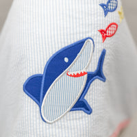 Child wearing a white hooded towel with a blue shark design, 3 Marthas