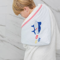 Child wearing a white hooded towel with a blue shark design on a marble background, 3 Marthas