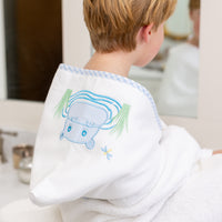 Child wrapped in hooded towel featuring a blue hippo applique sitting on bathroom counter, 3 Marthas