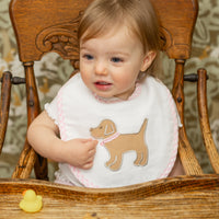 Girl wearing bib featuring puppy applique with pink trim, 3 Marthas