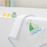 Bath mat with sailboat design on a white tub with rubber duck toys, 3 Marthas