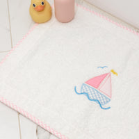 Bath mat with pink sailboat design, rubber duck, and bottle on a tiled floor, 3 Marthas