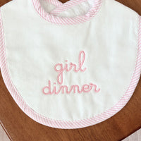 Baby bib with 'girl dinner' text on a wooden surface