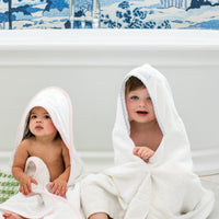 3 Marthas white terrycloth hooded towel with pink dino applique and pink trim for girls. White terrycloth hooded towel with blue dino applique and blue trim for boys.
