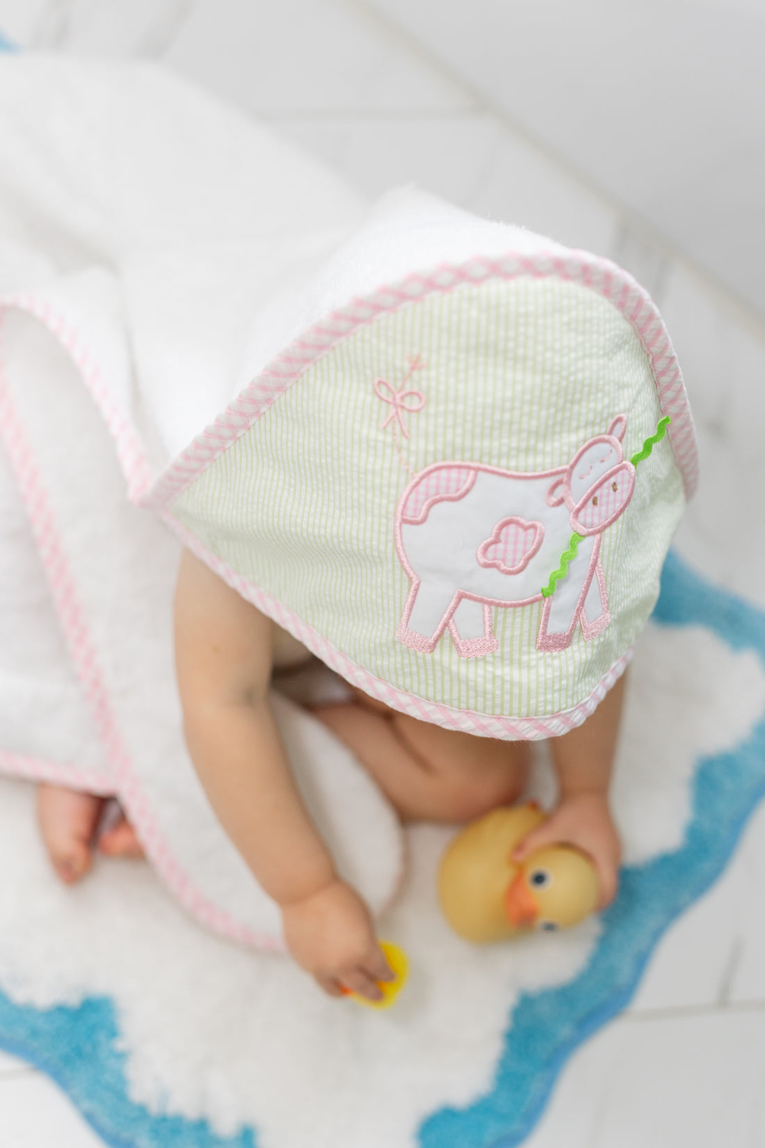 Hooded towel on baby outside of tub playing with rubber ducks, 3 Marthas