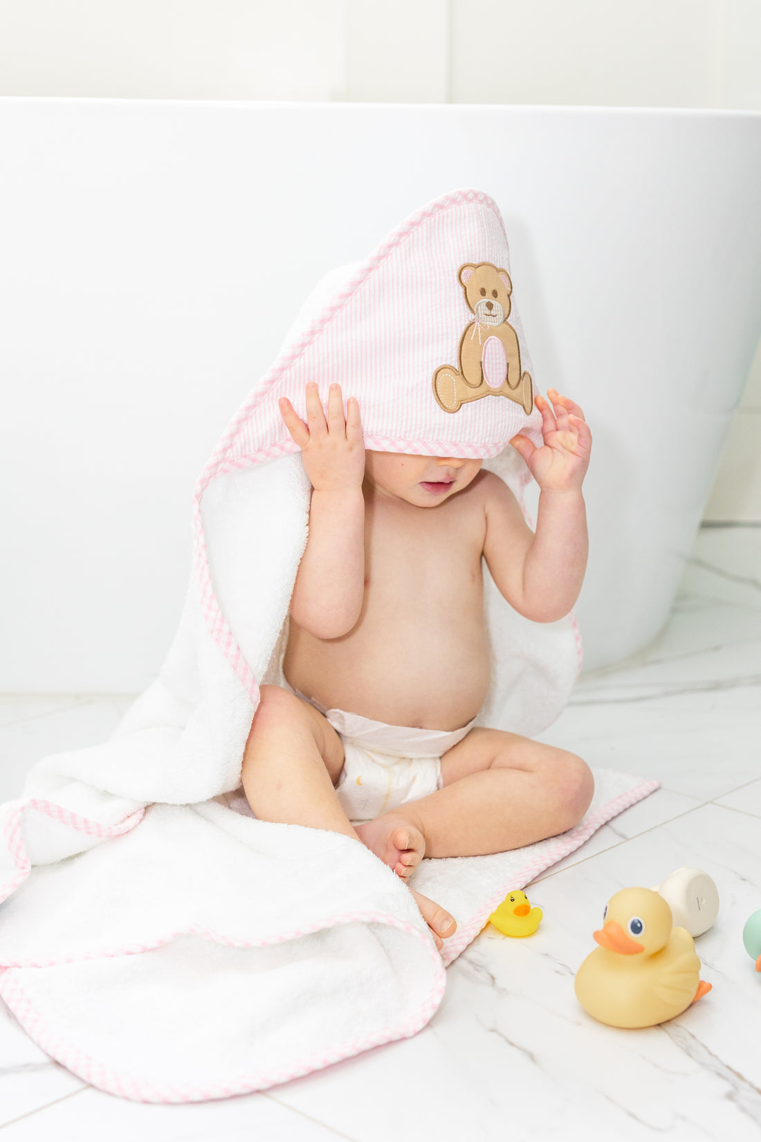 Baby in hooded towel outside of tub, 3 Marthas