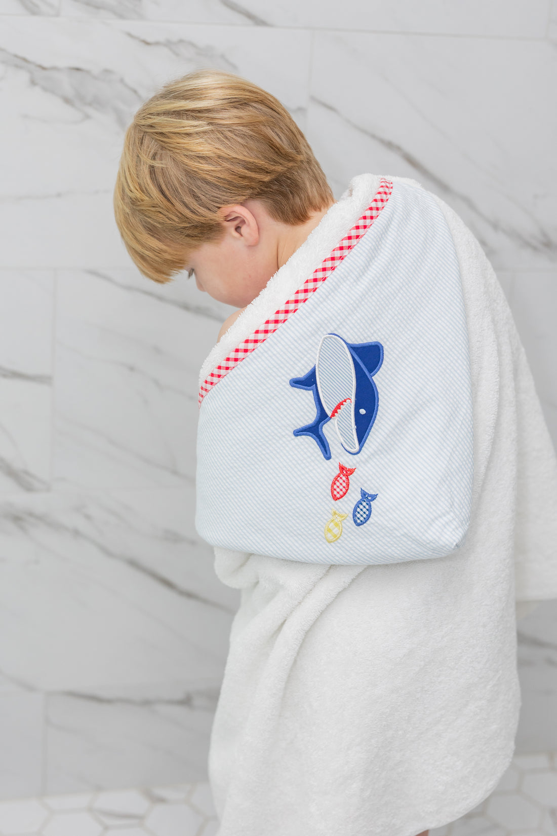 Child wearing a white hooded towel with a blue shark design on a marble background, 3 Marthas