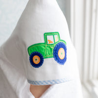 Child wrapped in hooded towel featuring a tractor applique, 3 Marthas