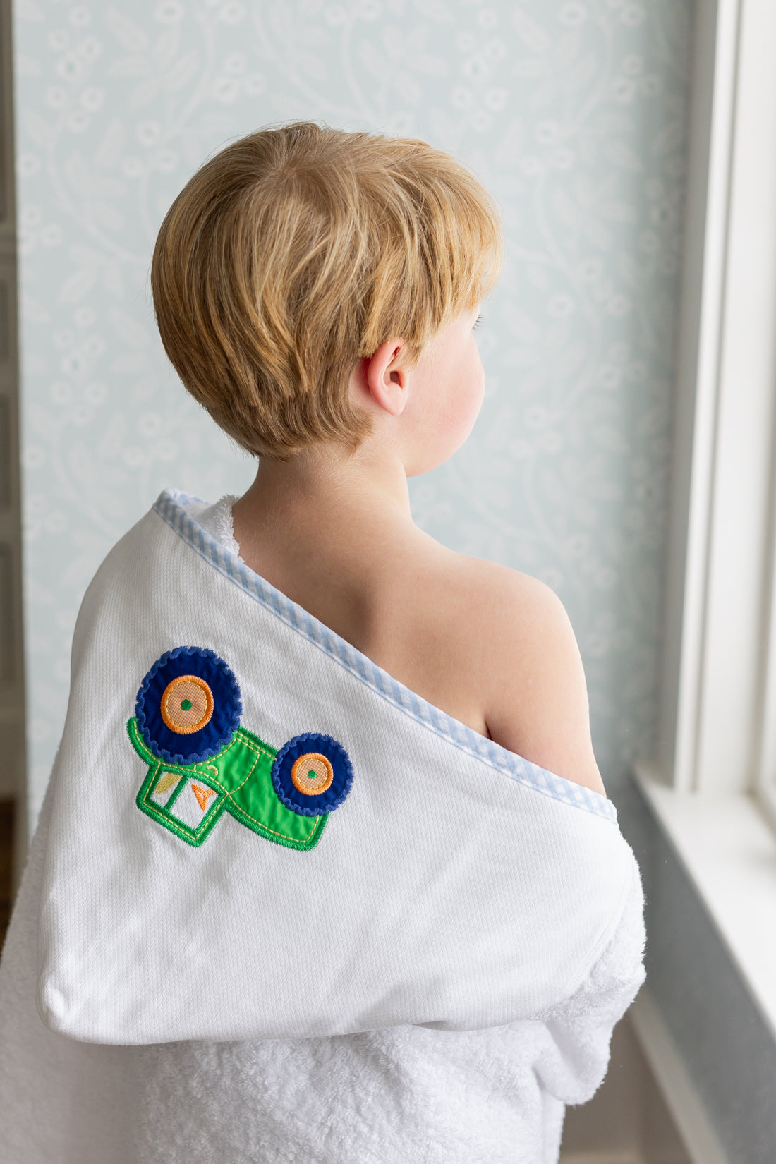 Child wrapped in hooded towel featuring a tractor applique, 3 Marthas