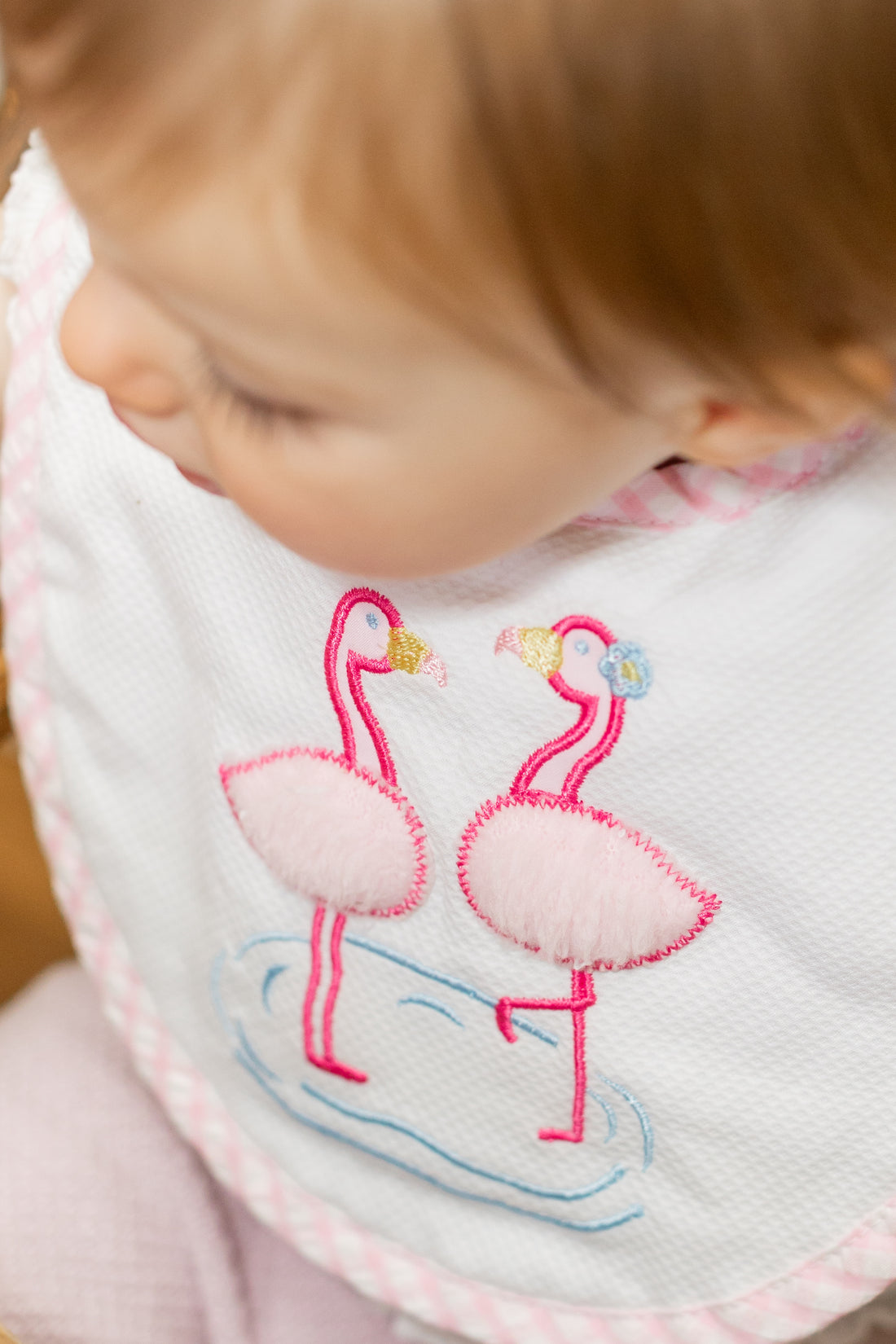 Baby wearing a bib with pink flamingo design, 3 Marthas