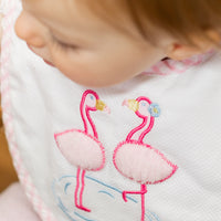 Baby wearing a bib with pink flamingo design, 3 Marthas