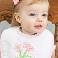 Baby sitting in a wooden chair wearing a bib with strawberry floral design, 3 Marthas