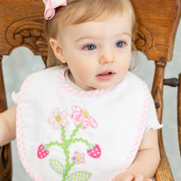 Baby wearing a bib with strawberry floral design sitting in a wooden high chair, 3 Marthas
