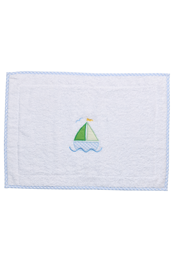 White terry bath mat with a blue sailboat applique