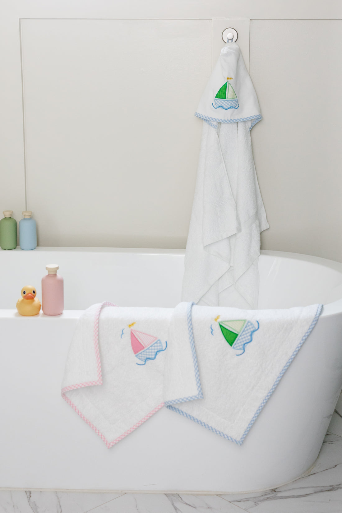 White bath mats with sailboat designs hanging over a bathtub, 3 Marthas