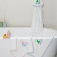White bath mats with sailboat designs hanging over a bathtub, 3 Marthas
