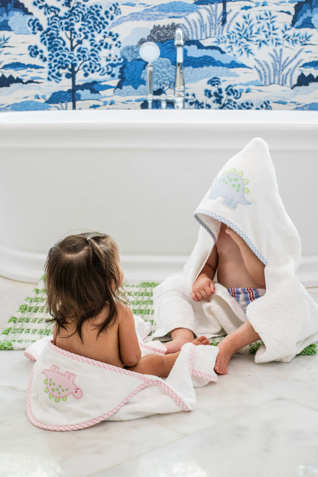 3 Marthas white terrycloth hooded towel with pink dino applique and pink trim for girls. White terrycloth hooded towel with blue dino applique and blue trim for boys. 